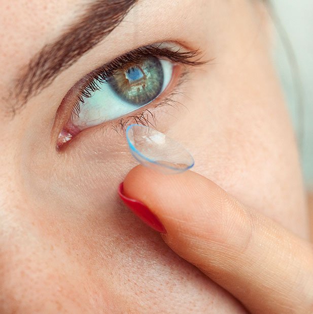 Kontaktlinse auf dem Finger am Auge